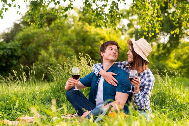 Pareja con copas de vino abrazando en la naturaleza