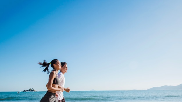 Pareja corriendo en la playa bajo el sol