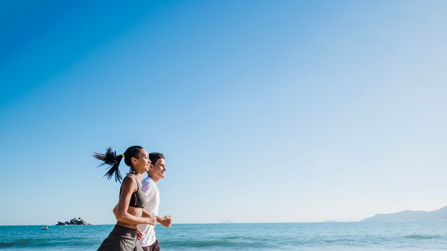 Pareja corriendo en la playa bajo el sol