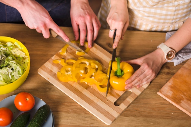 Pareja cortando pimiento amarillo para ensalada