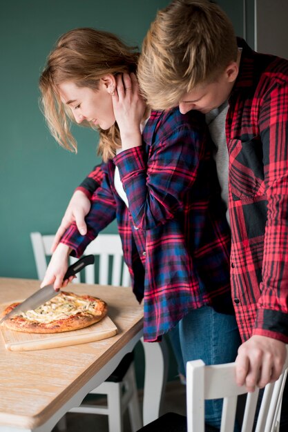 Foto gratuita pareja cortando pizza