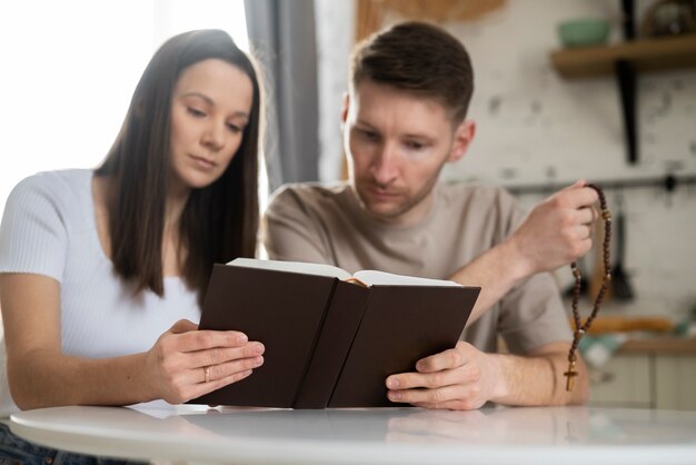 Pareja cristiana de tiro medio leyendo la biblia juntos