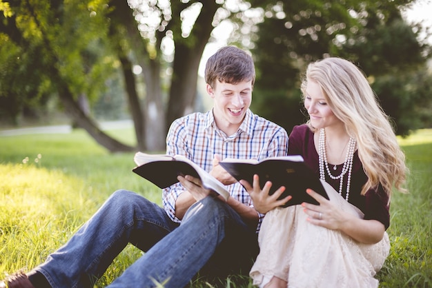 Foto gratuita pareja de cristianos blancos disfrutando de la lectura de la biblia en medio de un campo