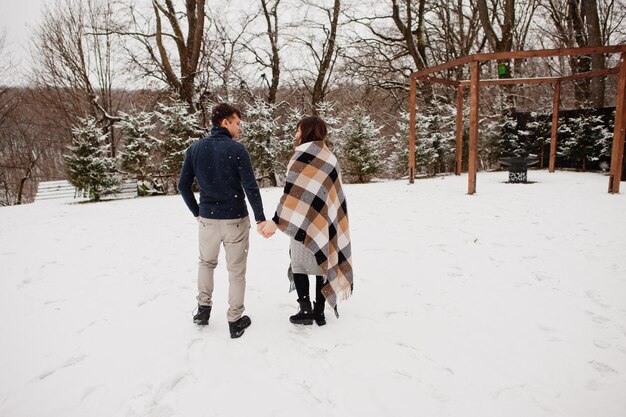 Pareja cubierta de manta en el día de invierno pasando tiempo juntos enamorados