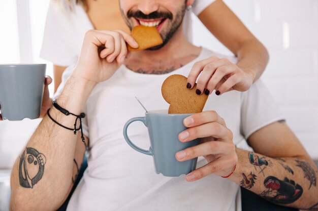 Pareja de cultivo sumergiendo galletas en taza