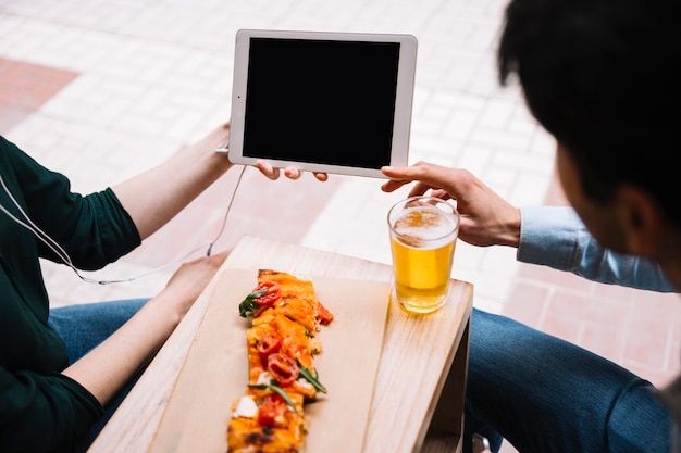 Pareja de cultivos con tableta y comida callejera