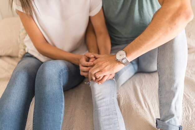 Pareja de cultivos tocando las manos en la cama