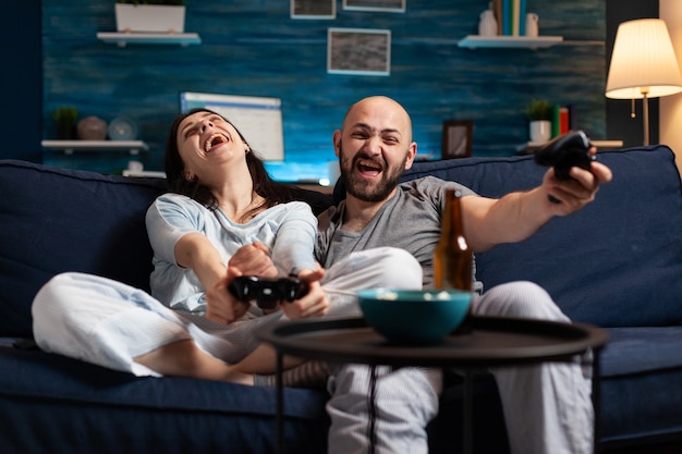 Pareja decidida enfocada jugando videojuegos de fútbol tarde en la noche