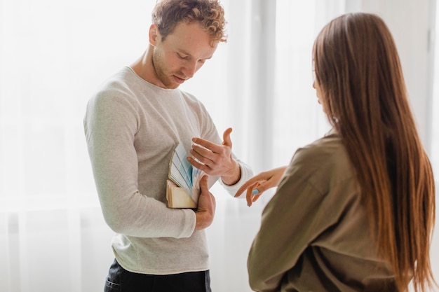 Pareja decidiendo redecorar la casa con paleta de pintura