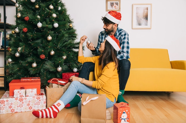 Pareja decorando árbol de navidad en salón