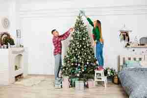 Foto gratuita pareja decorando árbol de navidad