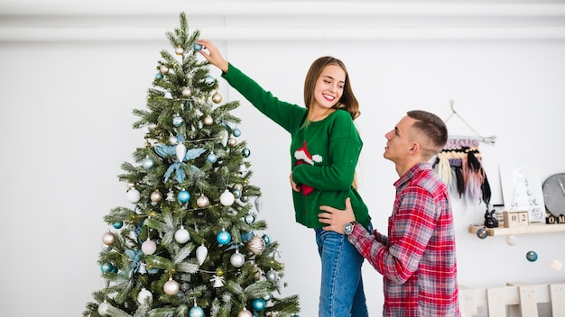 Pareja decorando árbol de navidad