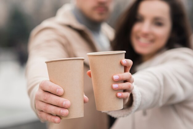 Pareja Defocused sosteniendo tazas de café