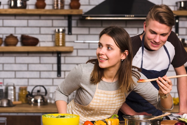 Pareja degustación de comida cocinada.