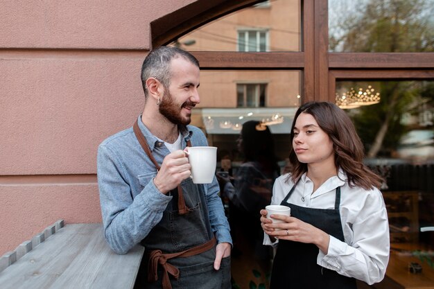 Pareja en delantales disfrutando de café afuera