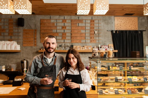 Pareja en delantales posando con tazas de café