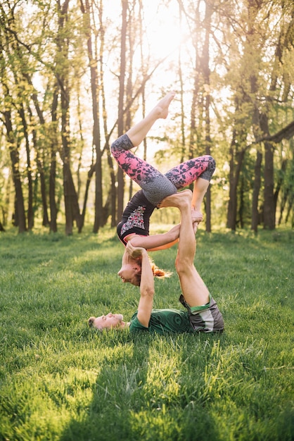 Pareja deportista practicando acro yoga en pasto verde