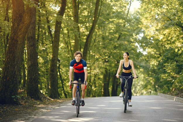 Pareja deportiva andar en bicicleta en el bosque de verano