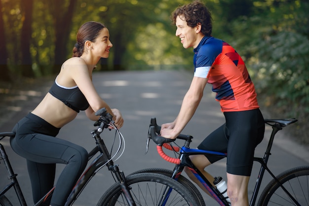 Pareja deportiva andar en bicicleta en el bosque de verano