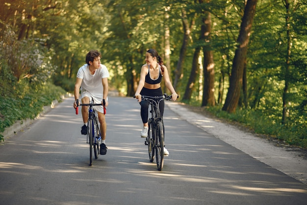 Pareja deportiva andar en bicicleta en el bosque de verano