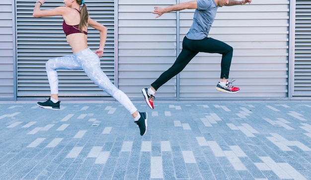 Pareja deportiva pareja corriendo y saltando en el aire