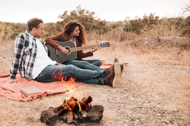 Pareja descansando al aire libre junto a una fogata