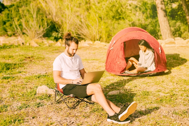 Foto gratuita pareja descansando en camping y trabajando a distancia.