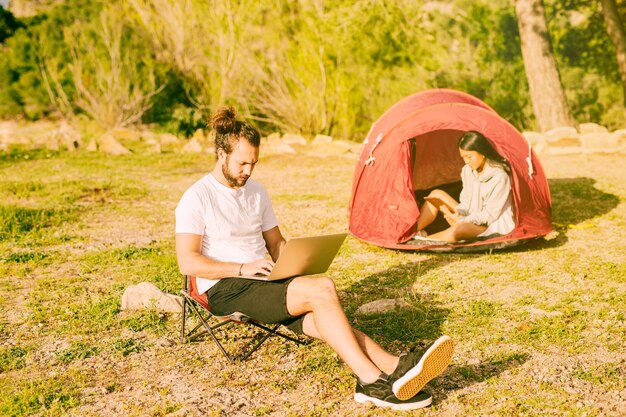 Pareja descansando en camping y trabajando a distancia.