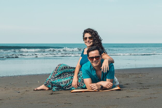 Pareja descansando en la playa de arena