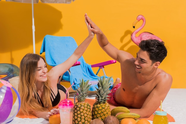 Pareja descansando en la playa con frutas