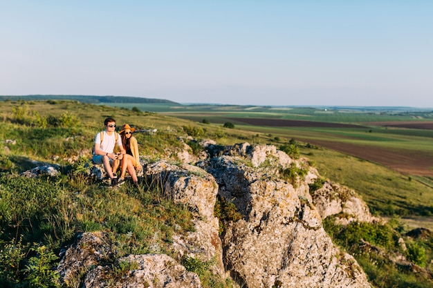 Pareja descansando en la roca después de ir de excursión