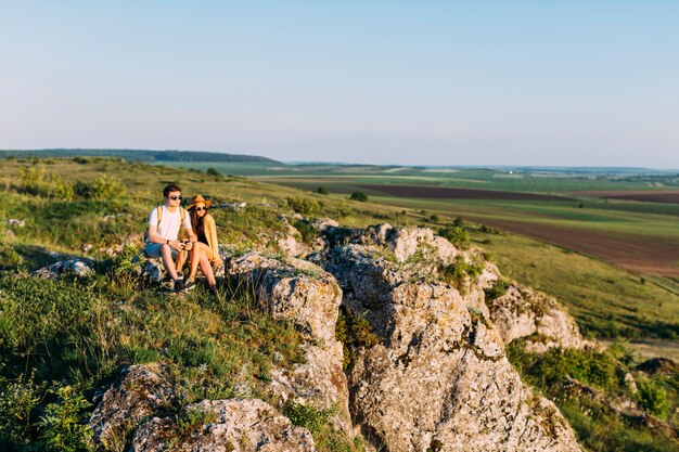 Pareja descansando en la roca después de ir de excursión