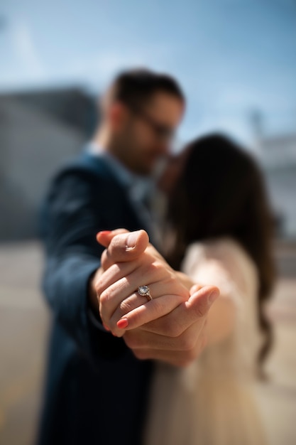 Pareja desenfocada en la ciudad tomados de la mano y mostrando el anillo de compromiso