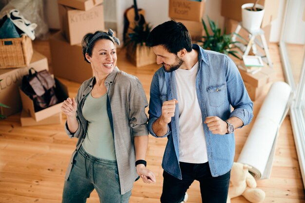 Pareja despreocupada bailando mientras se muda a su nuevo apartamento