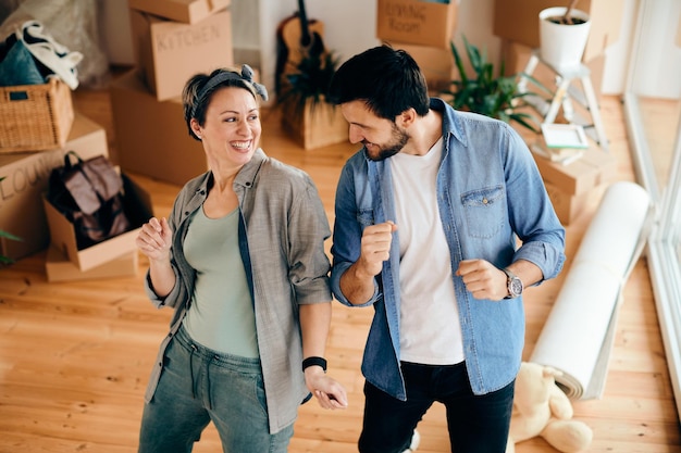 Pareja despreocupada bailando mientras se muda a su nuevo apartamento