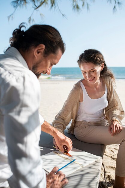 Pareja dibujando en la playa durante las vacaciones