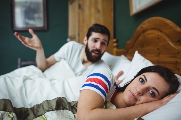 Pareja discutiendo en la cama en el dormitorio