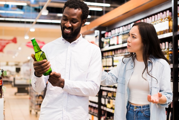 Pareja discutiendo sobre la cerveza en la tienda de comestibles