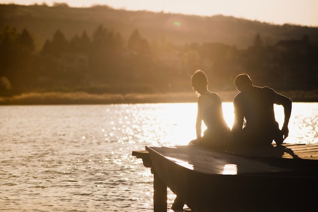 Pareja disfrutando del atardecer en el embarcadero