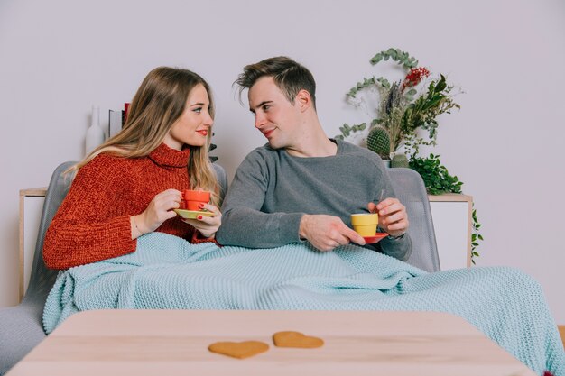 Pareja disfrutando de bebidas calientes en el sofá