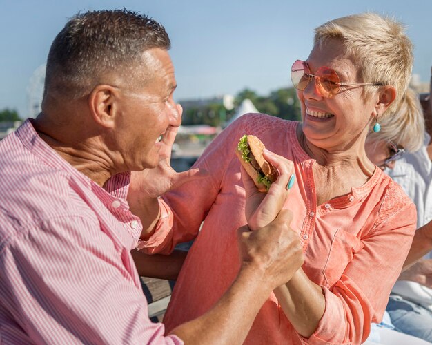 Pareja disfrutando de una hamburguesa al aire libre