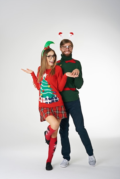 Pareja divertida vistiendo suéteres de Navidad extraños