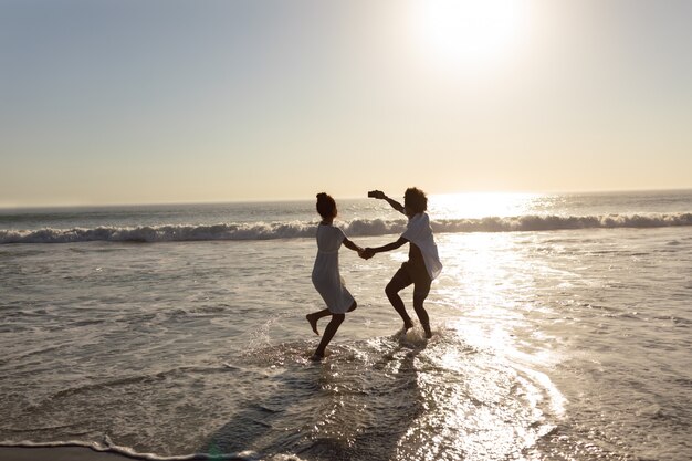 Pareja divirtiéndose mientras toma selfie con teléfono móvil en la playa