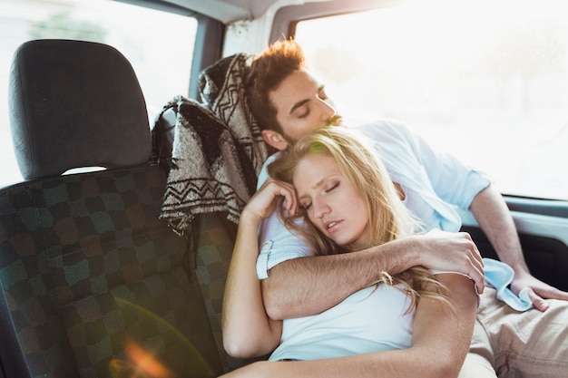 Pareja durmiendo en el asiento trasero