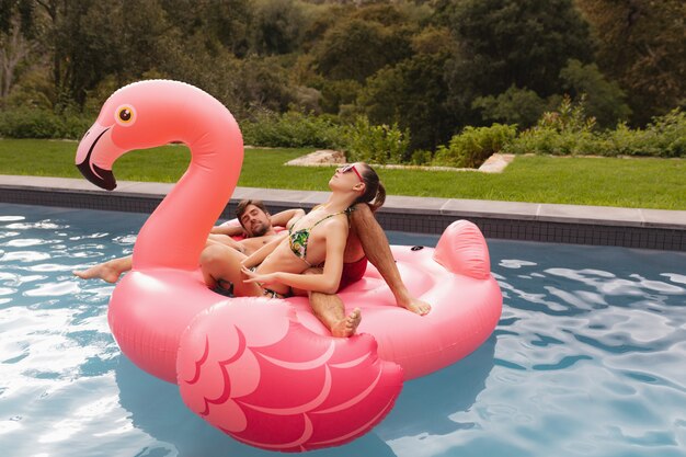 Pareja durmiendo juntos en un tubo inflable en la piscina