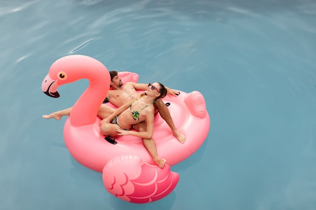 Pareja durmiendo juntos en un tubo inflable en la piscina