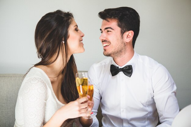 Pareja elegante brindando y sonriendo a la cara del otro