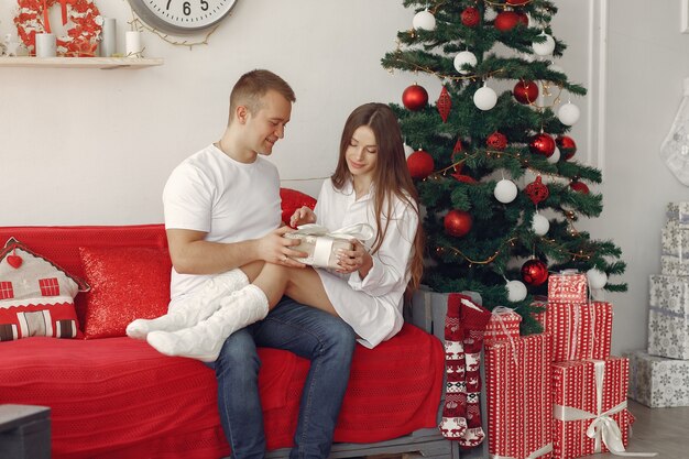 Pareja elegante en casa cerca del árbol de Navidad