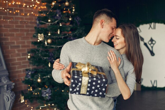 Pareja elegante en casa cerca del árbol de Navidad