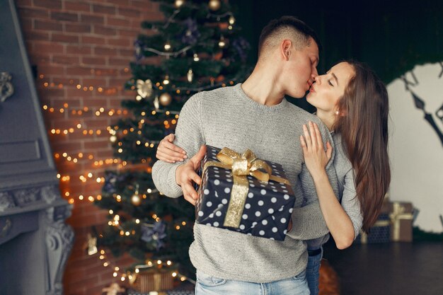 Pareja elegante en casa cerca del árbol de Navidad